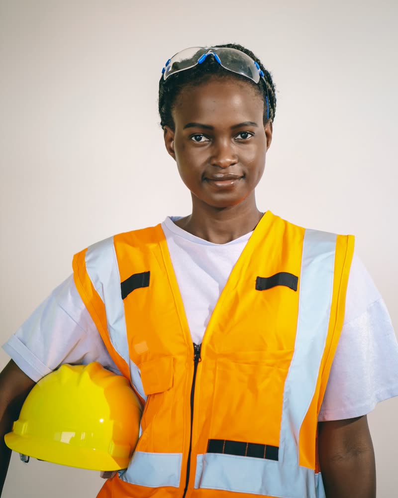 An artisan in a hi-vis vest holding a hard hat, looking to camera